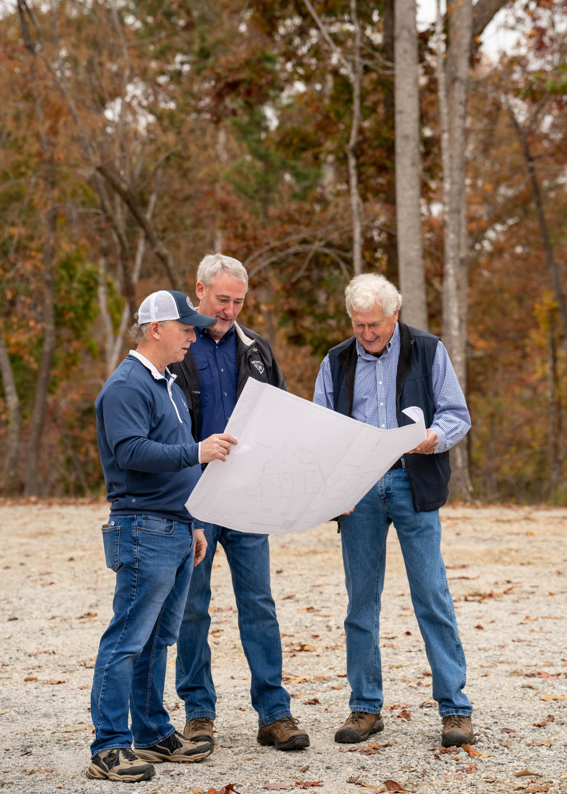Three land brokers looking down at a plat of a property.