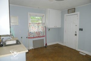Bright kitchen area featuring a sink, window with patterned curtain, and door leading outside in a 2 bed, 1 bath home. Bright kitchen area featuring a sink, window with patterned curtain, and door leading outside in a 2 bed, 1 bath home.