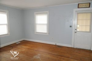 Bright, empty living room with hardwood floors, blue walls, and windows, showcasing potential for a 2 bed, 1 bath home. Bright, empty living room with hardwood floors, blue walls, and windows, showcasing potential for a 2 bed, 1 bath home.