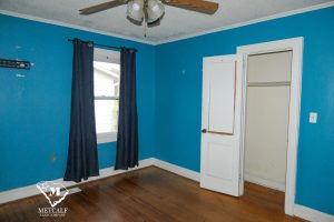 Bright blue bedroom featuring a ceiling fan, window with curtains, and an open closet door. Bright blue bedroom featuring a ceiling fan, window with curtains, and an open closet door.