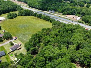 Aerial view of a multi-use property with open land and wooded areas adjacent to Interstate 85. Aerial view of a multi-use property with open land and wooded areas adjacent to Interstate 85.