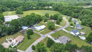 Aerial view of a multi-use property with residential homes and open land near Interstate 85, surrounded by greenery. Aerial view of a multi-use property with residential homes and open land near Interstate 85, surrounded by greenery.