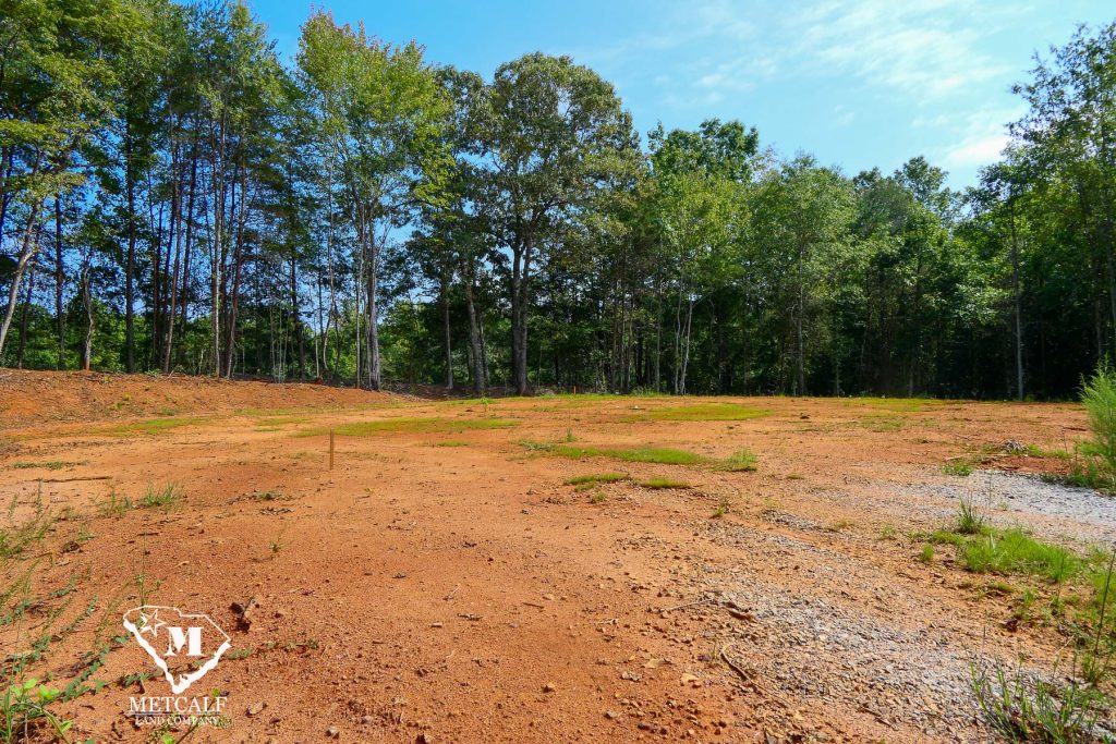 Cleared 2.5-acre homesite in Campobello, surrounded by trees and blue sky, ready for development.