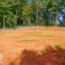 Cleared 2.5-acre homesite in Campobello, surrounded by trees and featuring red soil with patches of grass.